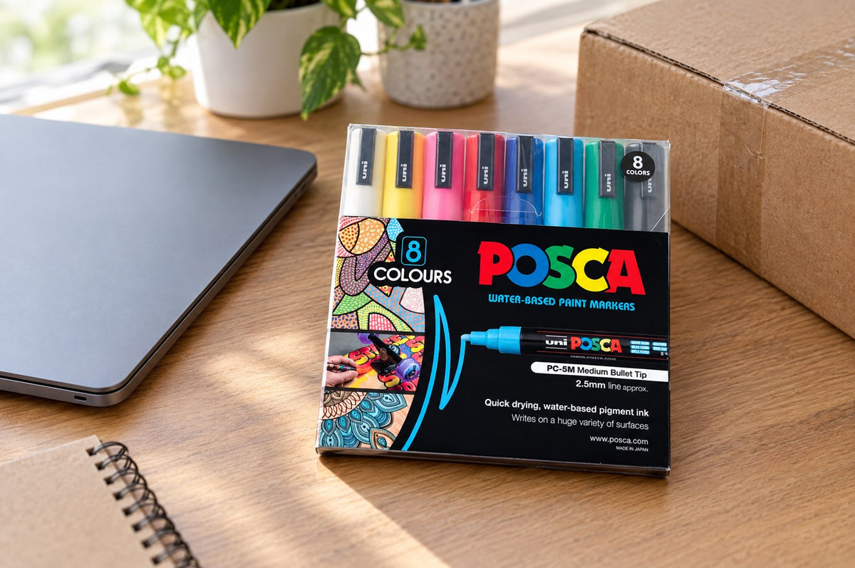 POSCA markers beside a laptop on a home desk