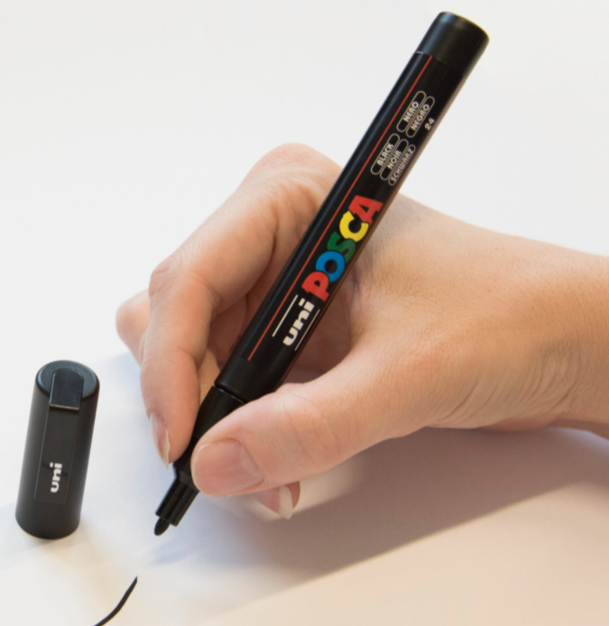 Artist drawing fine detail on paper with a POSCA PC-3M marker