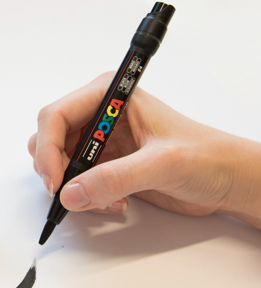 POSCA PCF-350 brush marker in hand making a black brush stroke on paper
