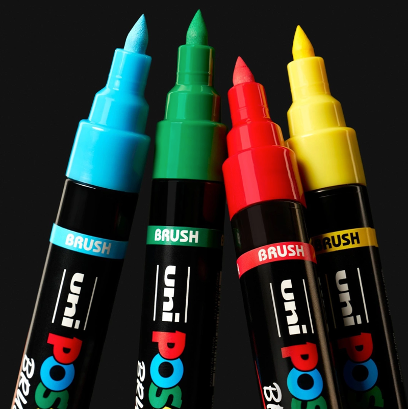 Four POSCA PC-5BR brush markers in blue, green, red and yellow with tips showing