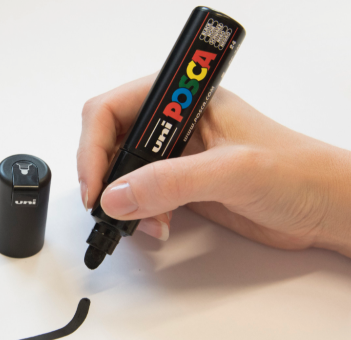Artist drawing on a white surface with a POSCA PC-7M marker
